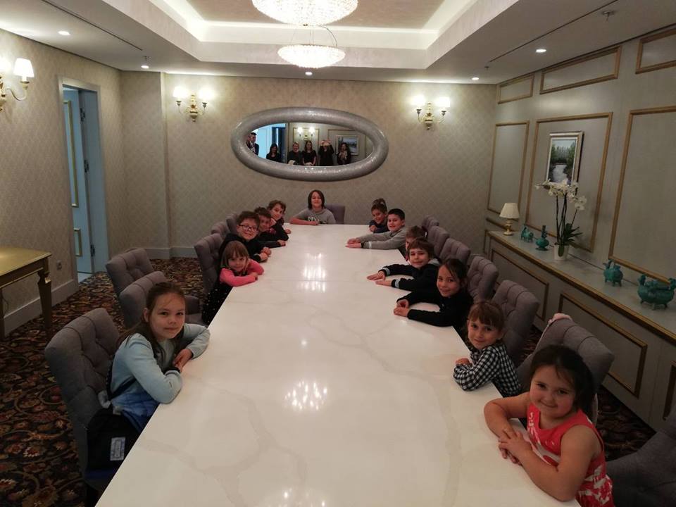 djeca sjede za dugim stolom